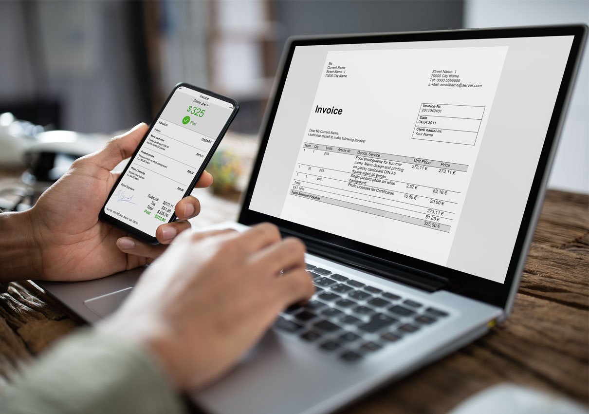 A business owner looking at an invoice on their phone and laptop