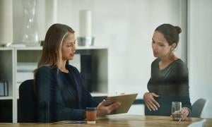 a pregnant woman talking to an advisor and checking together a document